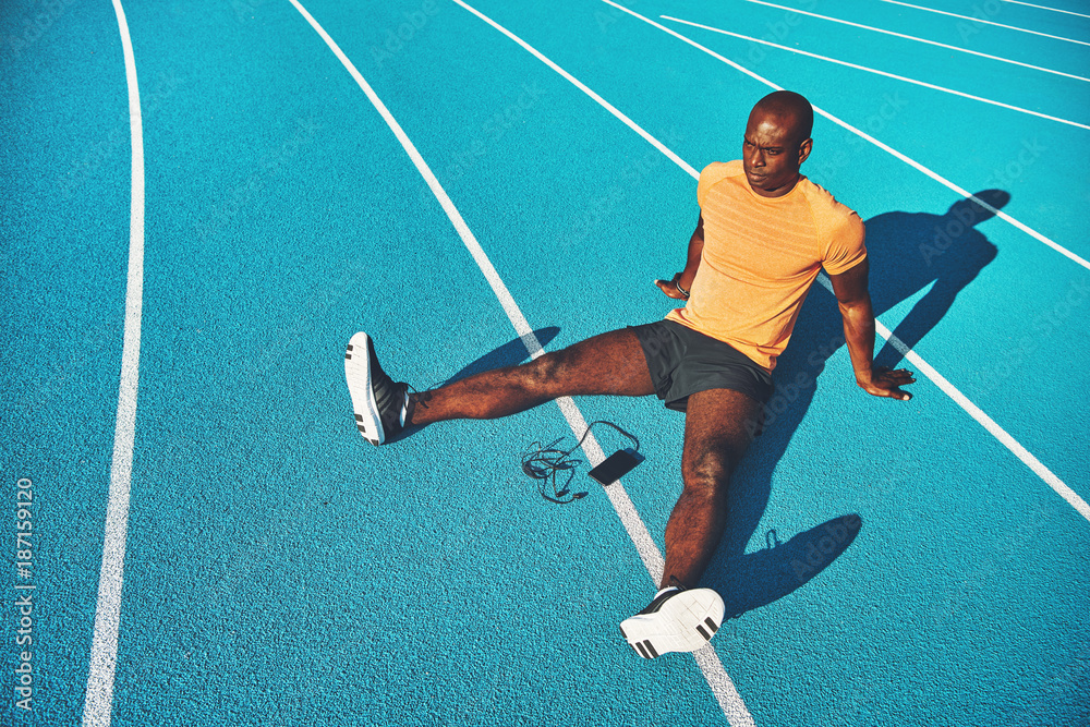 Fototapeta Young athlete relaxing on running track lanes before training