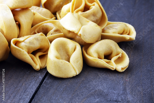 Raw cheese filled tortellini pasta on wooden background