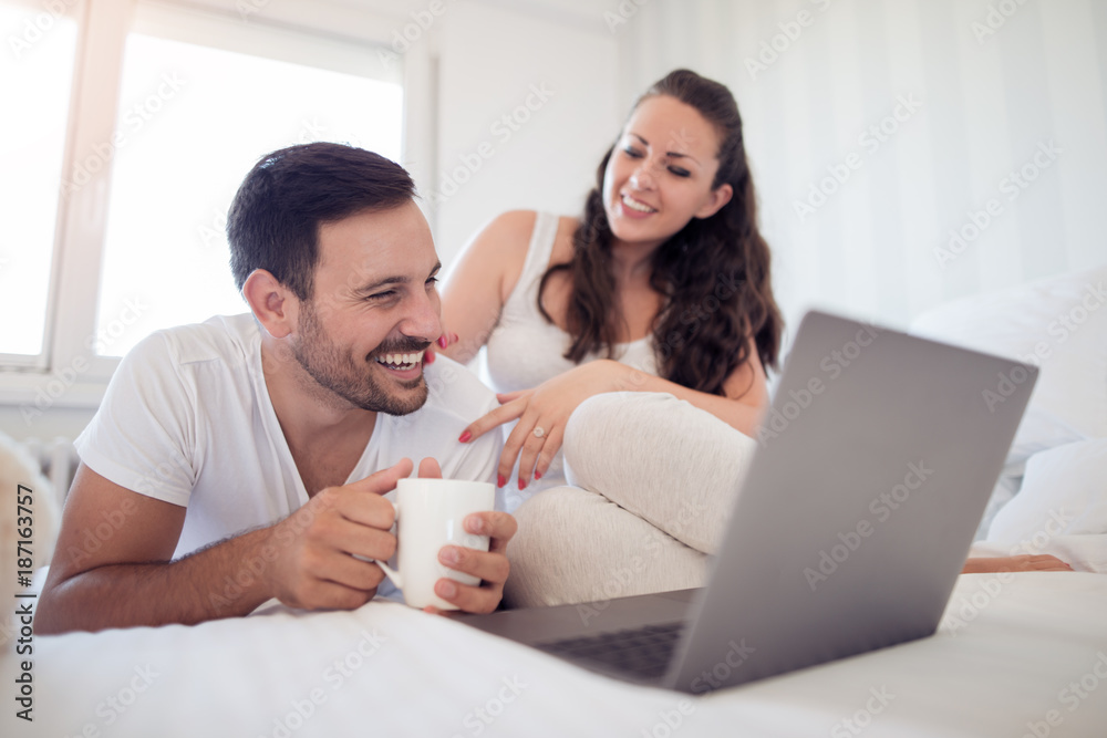 Young couple with laptop in the bed Young couple with laptop in the bed