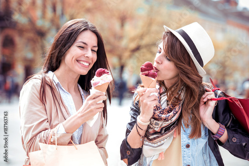 Two beautiful girls eating ice cream and shopping.