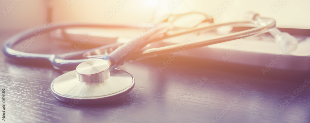 Stethoscope and laptop keyboard on desktop in hospital,relax time doctor,medical concept,selective focus,vintage color.morning light - obrazy, fototapety, plakaty 