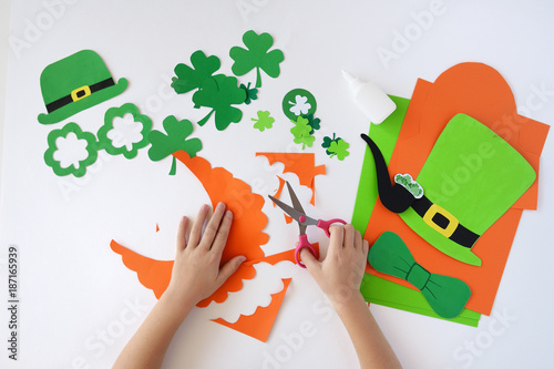 Top view.  Children's hands cut out a mask from paper for a St. Patrick's Day photo