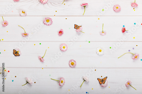 Daisy flowers and confetti in wooden background.