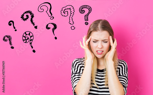 Question Marks with young woman feeling stressed on a pink background