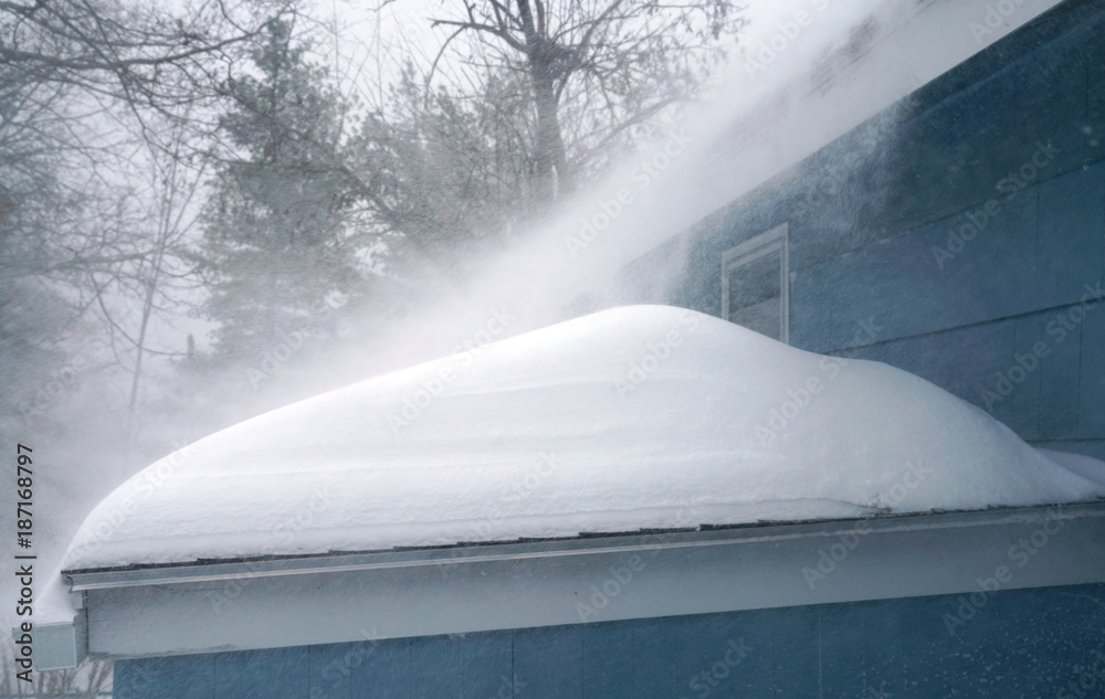 Naklejka premium Winter wind blowing thick snow on the roof in blizzard