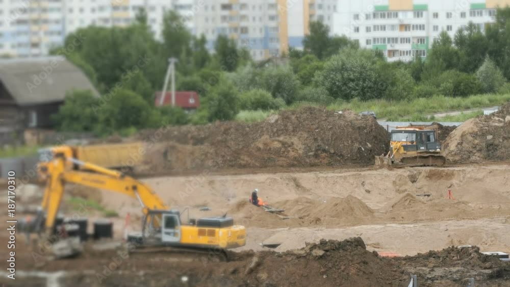 Construction vehicles and builders on construction site in a summer season Construction vehicles and builders on construction site in a summer season