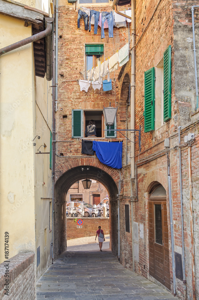 Walking trough an archway in a quiet alley - Siena, Italy