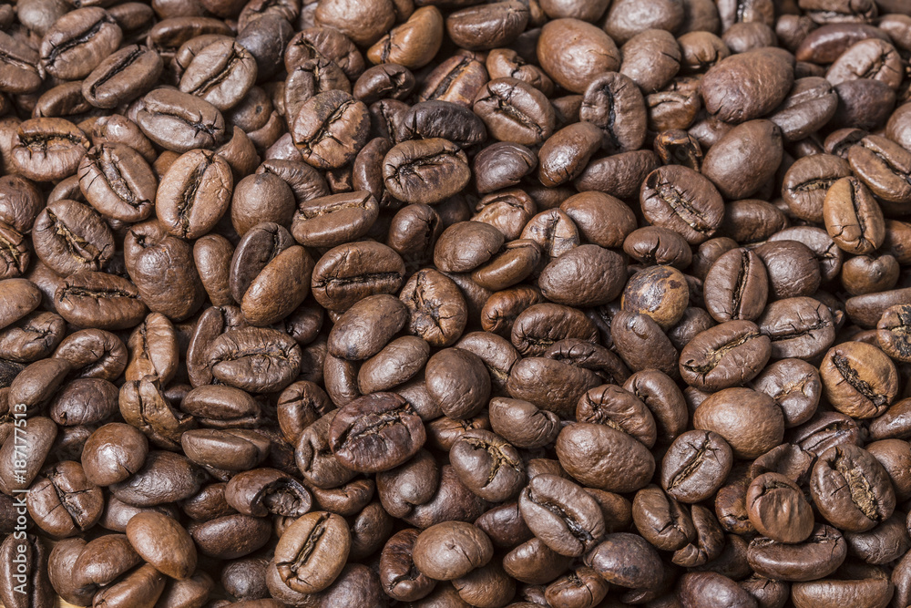 Many roast brown coffee grains texture close up on an abstract background