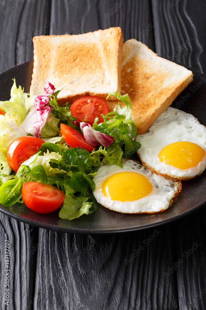 hearty breakfast: fried eggs with fresh vegetable salad and toast close-up. vertical hearty breakfast: fried eggs with fresh vegetable salad and toast close-up. vertical
