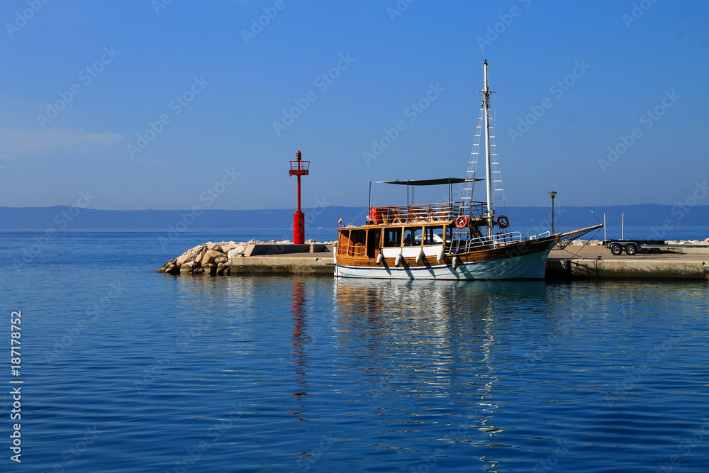 Lighthouse and small cruiser ship in small marine in Baska Voda , Croatia