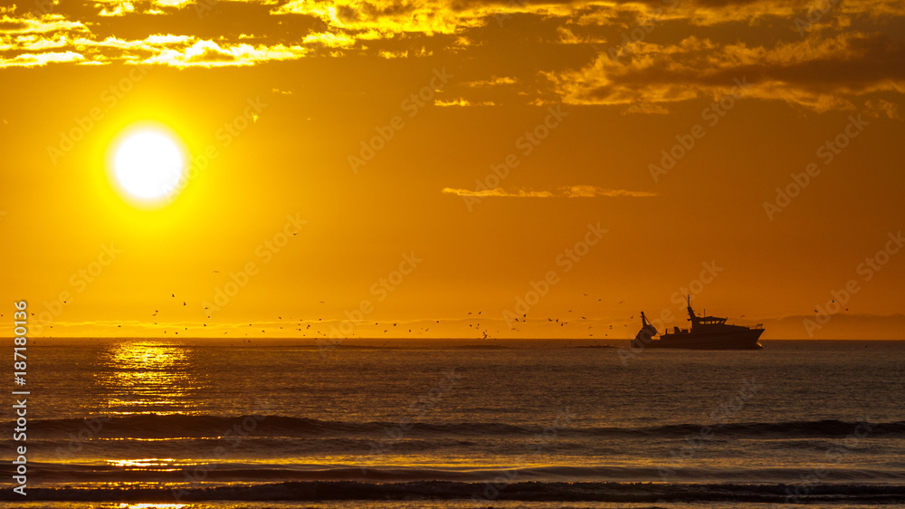 bateau revenant de la pêche au coucher de soleil