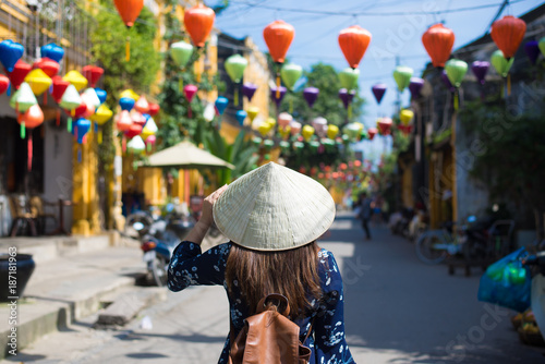 Tourist woman is wearing Non La (Vietnamese tradition hat) and enjoy sightseeing at Heritage village in Hoi An city in Vietnam. photo