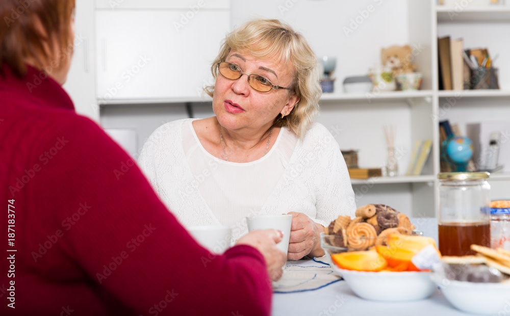 Positive old women drinking tea at the table