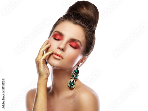 Beautiful woman with a colorful makeup is wearing earrings with green emeralds