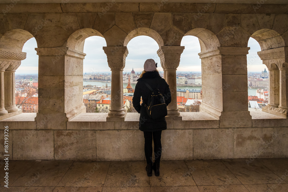 Young woman is admiring Hungarian Parliament Building from Fisherman's Bastion in Budapest, Hungary