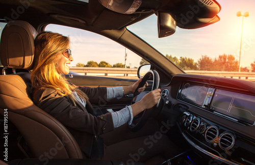 Beautiful businesswoman driving car at sunset