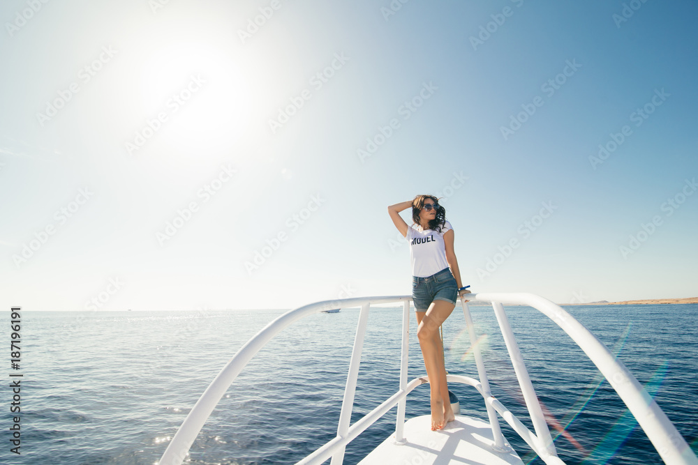 young beautiful female model standing on the deck of a yacht at sea. young beautiful female model standing on the deck of a yacht at sea.