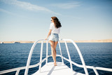 Beauty woman standing on yacht nose on sea background