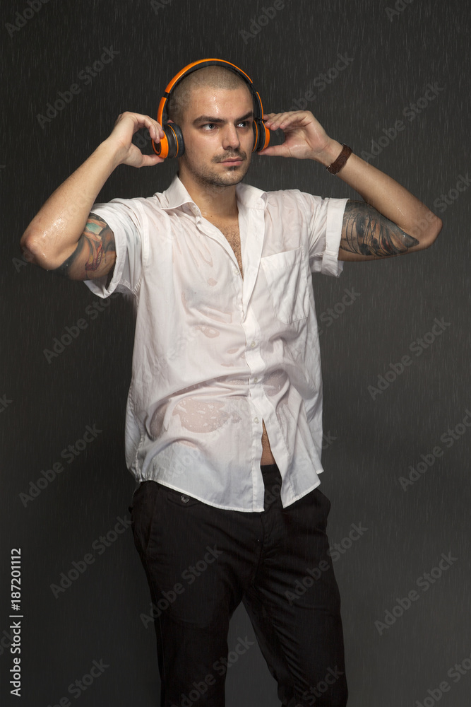 Portrait of a wet young man in headphones under the spray