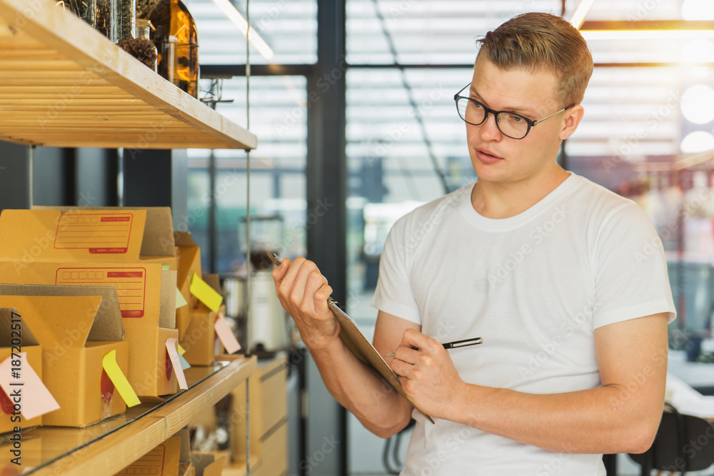 Obraz premium Young man with clipboard checking orders at warehouse