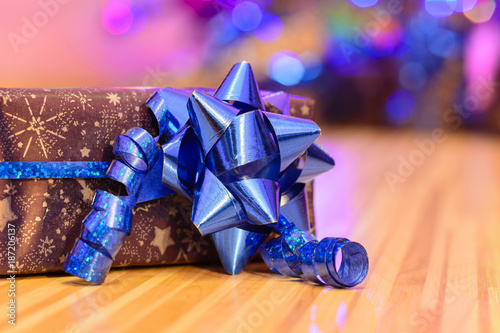 Christmas gift wrapped in purple wrapping paper bound with blue ribbon and ornament photo