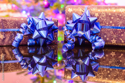 Christmas gifts wrapped in purple wrapping paper bound with blue ribbon and ornament photo