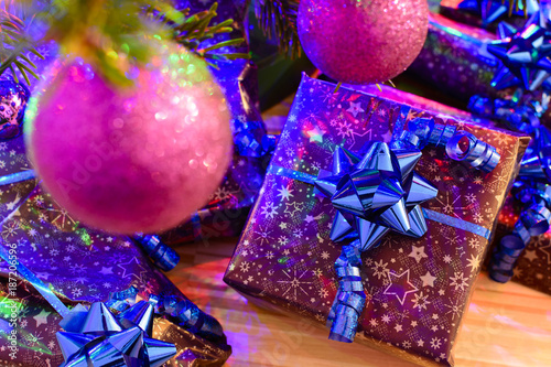 Christmas gifts wrapped in purple wrapping paper bound with blue ribbon and ornament photo