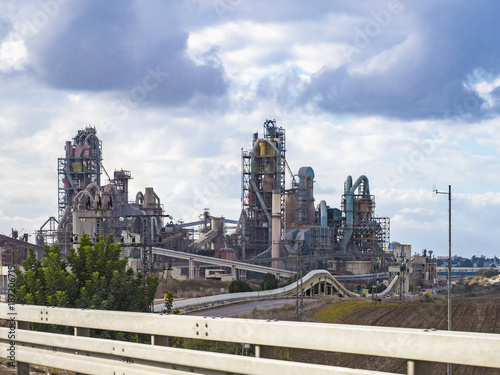 Production plant in sunlight amid a cloud of heaven. Cement production.