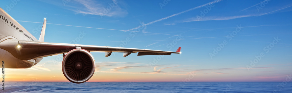 Fototapeta Szczegół skrzydło komercyjnego samolotu odrzutowiec lata above chmury w pięknym zmierzchu świetle.