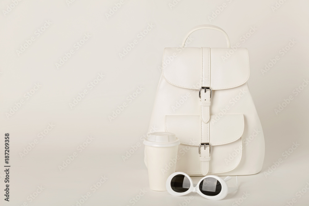 White female backpack and sunglasses on a white background.