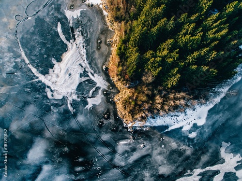 Aerial view of the winter snow forest and frozen lake from above captured with a drone in Finland.