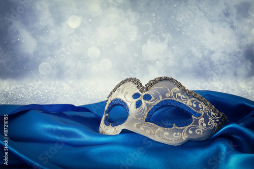 Image of elegant blue and gold venetian mask over blue silk fabric background.