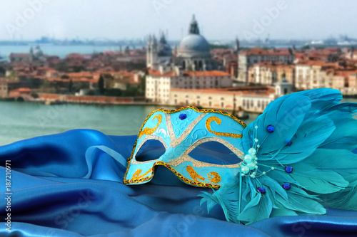 Image of elegant venetian mask on silk fabric in front of blurry Venice background.
