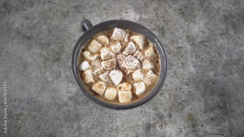 Ceramic cup of hot chocolate with marshmallow on gray table, falling cocoa Ceramic cup of hot chocolate with marshmallow on gray table, falling cocoa