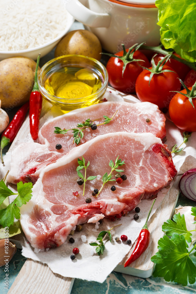 two pieces of pork on a cutting board and fresh ingredients, vertical two pieces of pork on a cutting board and fresh ingredients, vertical