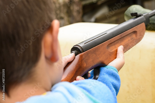 A little boy shooting from an air rifle to a target
