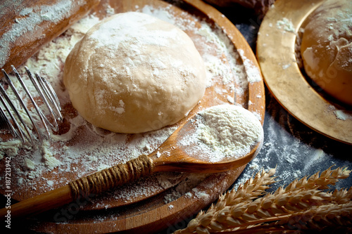 Dough with flour on an old background in a composition with kitchen accessories