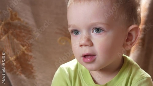 A cute little boy boy looks attentively at one point. Smiling and surprised at what he saw