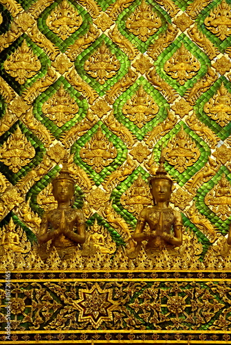 Detail of a wall from the Phra Mondop (the library), on Wat Phra Kaew temple in Bangkok, Thailand, with small tiles in a vibrant gold and emerald colors.