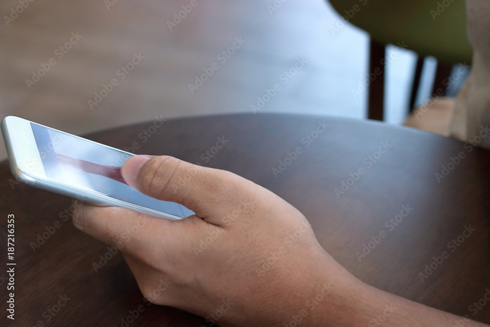 Close up mobile smart phone with blank screen on hands of unidentified people in coffee cafe.