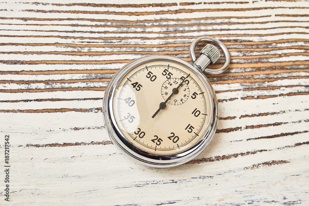 Retro stopwatch on rustic wooden background. Analog timing device for athletes and trainers.