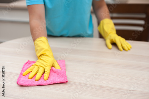 House cleaning. Closeup of housewife wiping furniture from dust in rubber gloves on her hands