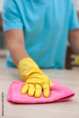 Closeup of employee of cleaning company wiping furniture from dust in rubber gloves on her hands