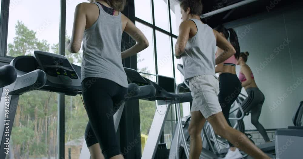 Training in a Gym/People training in a gym using treadmills and  Elliptical Cross. Training after work in the office. Caring for the health of the body. Slow motion