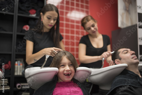 Hairdressers with little girls and man. Father and daughter at hairdresser