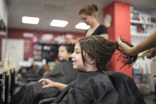 Hairdressers with little girls in beauty center saloon