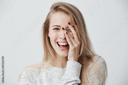 Fotografia Headshot of cute woman with dark eyes, blonde long hair, happy gentle smile rejoicing her success