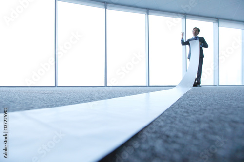 Office worker unrolling long sheet photo