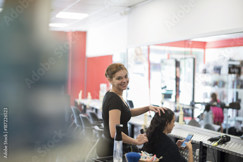 Fototapeta Naklejka Na Ścianę i Meble -  Hairdresser cuts and comb young womans hair