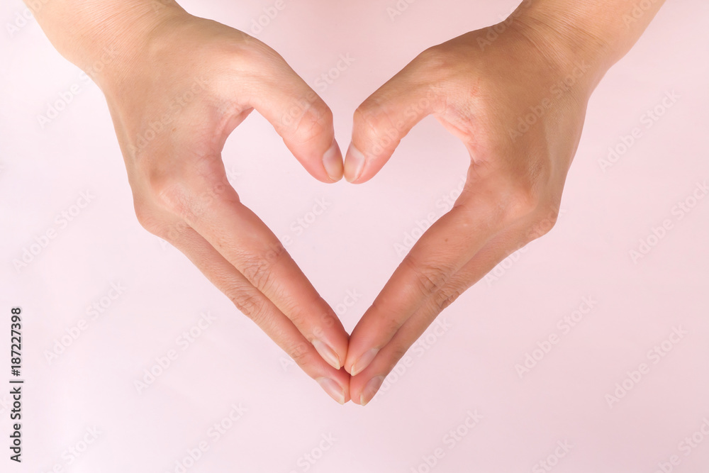 Woman hands make heart shape on pink background. Symbolic of love. Valentine theme. Woman hands make heart shape on pink background. Symbolic of love. Valentine theme.